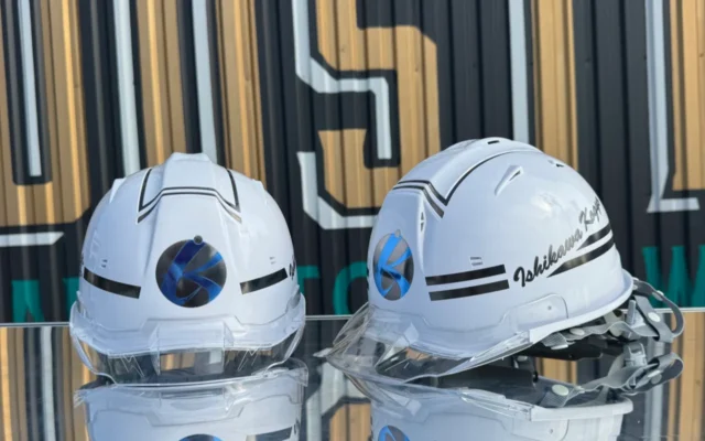 白いヘルメットに黒のラインとブルーのマーク、筆記体の社名をプリントした制作事例