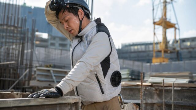 灼熱の中、工事現場で作業をする職人さん、空調服着用