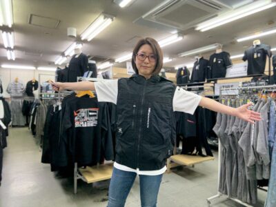 桑和スタッズのEFウェアのベストをダイマツ店舗で谷が着用し両手を広げてポーズ