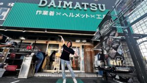 ダイマツ店舗の前でポーズをとる谷