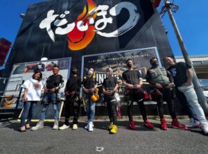 ダイマツの看板前で写真を撮る建設関係の職人さんたち