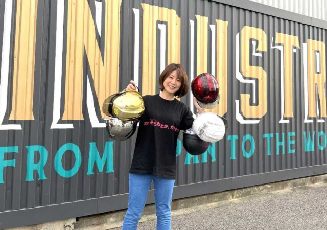 ヘルメットをたくさん手に持ち笑顔の谷